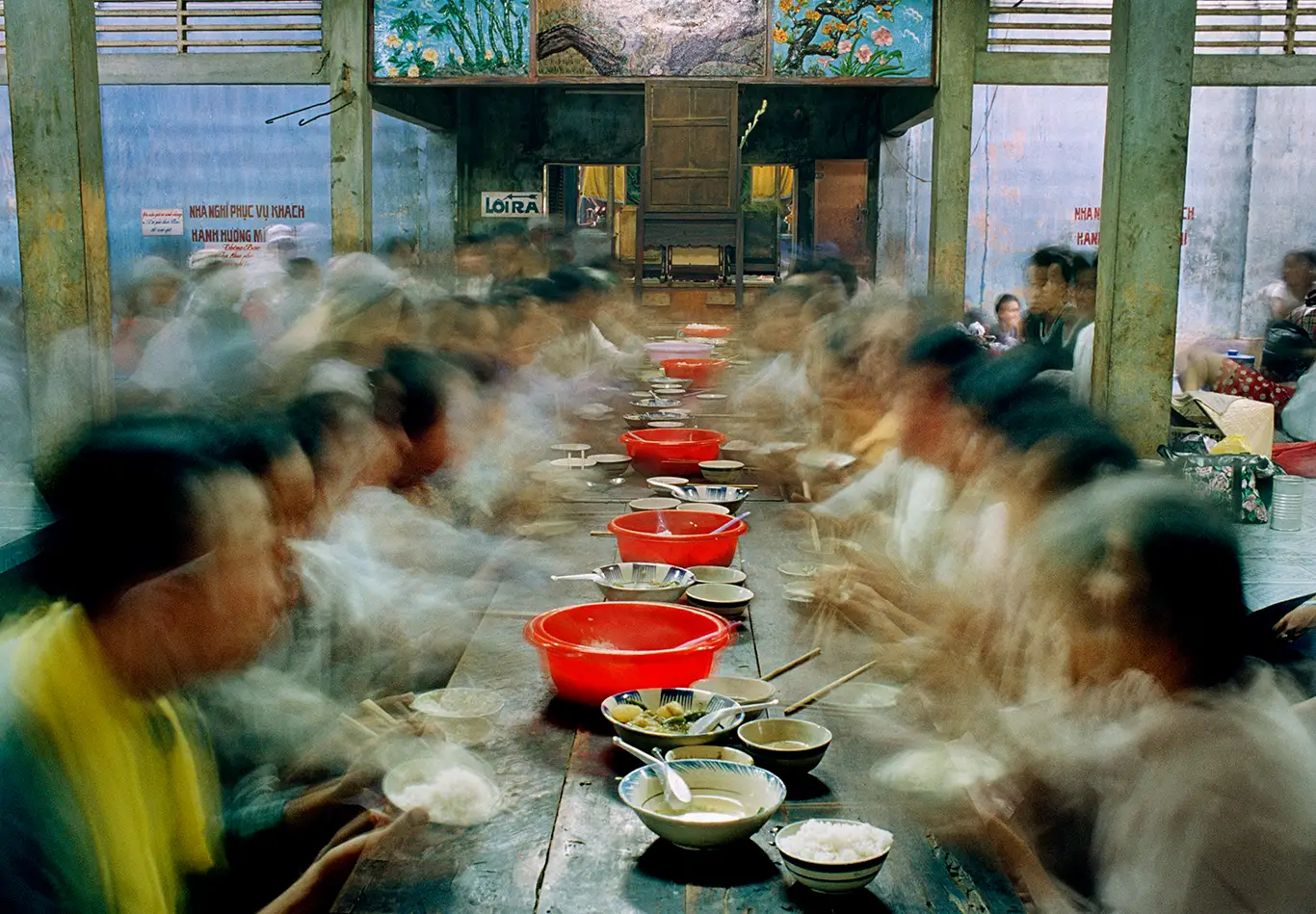 A table with lots of people around it, pilgrims, long exposure time, blurred figures