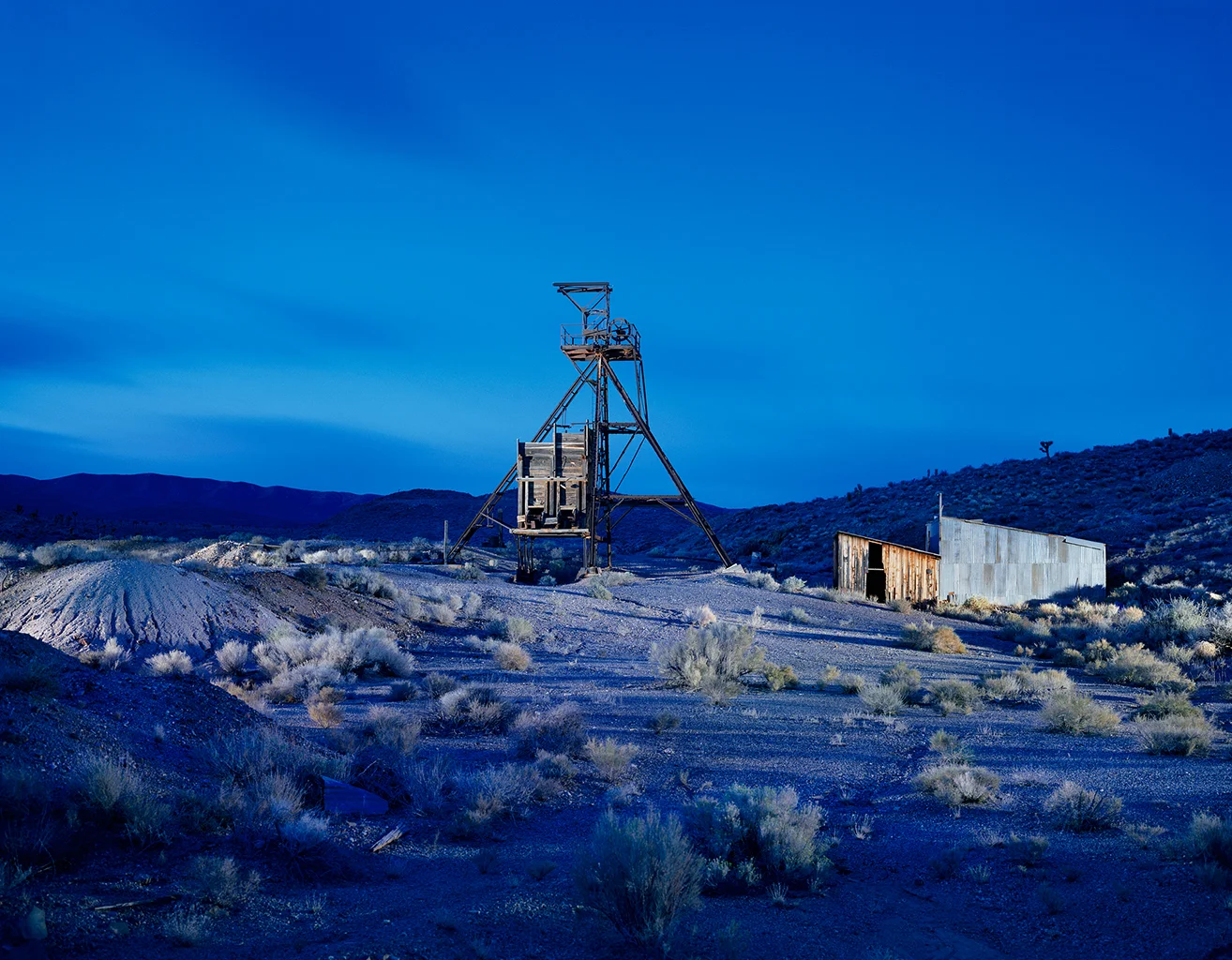 filigranes Fördergerüst aus Stahl und ein großer hölzerner Erzbunker der Dunfee Mine in der kargen Wüstenlandschaft von Gold Point, Nevada