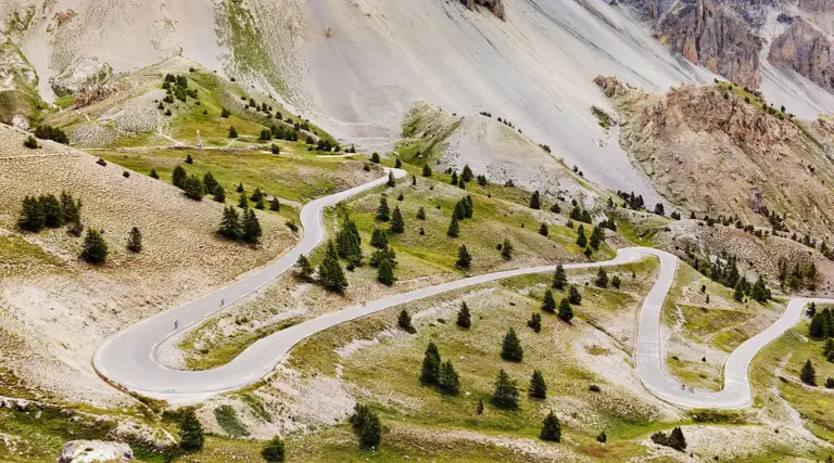 eine Bergstraße, die sich durch die karge Felslandschaft der Casse Déserte am südlichen Vorgebirge des Col de l'Izoard in den französischen Cottischen Alpen schlängelt