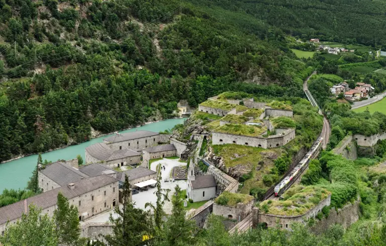 Zug der Pustertalbahn fährt durch die Festung Franzensfeste in Südtirol, Italien