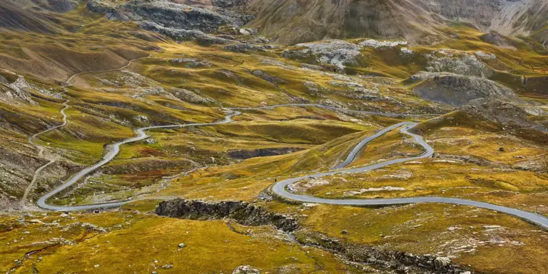 Straße durch die Herbstlandschaft an der Nordrampe des Alpenpass Col de la Bonette