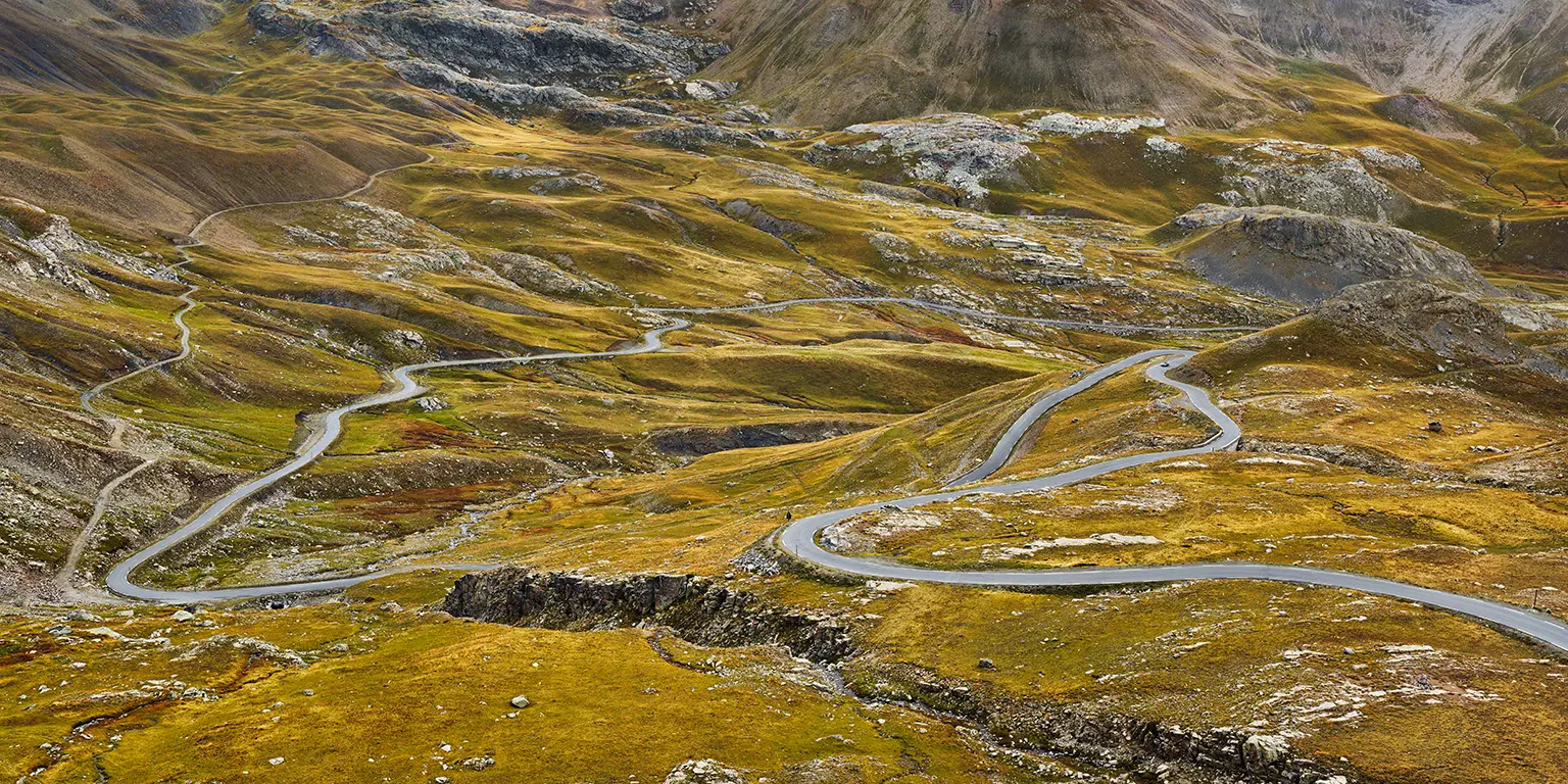 Straße durch die Herbstlandschaft an der Nordrampe des Alpenpass Col de la Bonette