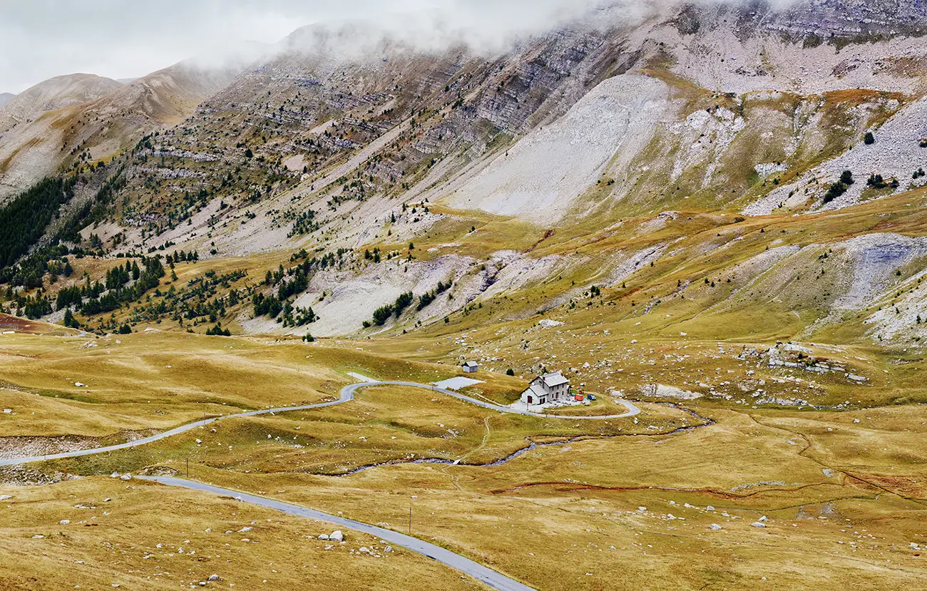 Nordrampe und Refuge am Alpenpass Col de la Cayolle in einer kargen, von schroffen Kalkfelsen und eiszeitlichen Geröllhalden geprägten Landschaft