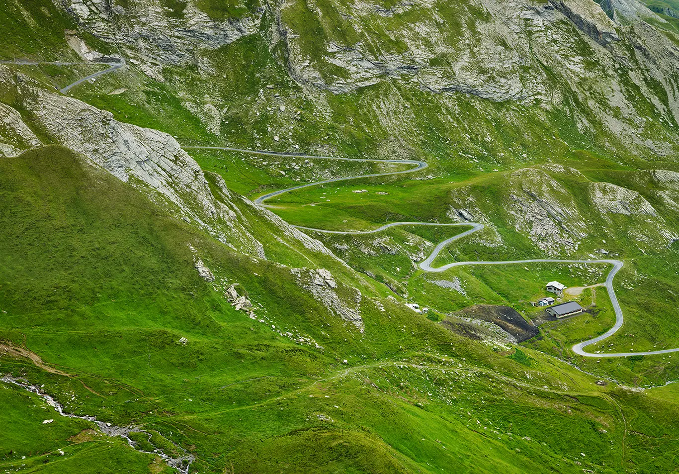 Straße des Alpenpass Colle dell’Agnello (Col Agnel) führt durch grüne Almwiesen Richtung Passhöhe