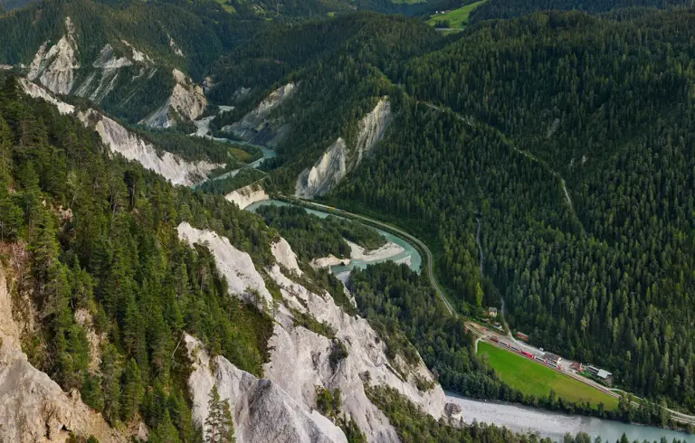 Bahnstrecke durch die Kalksteinklippen der Ruinaulta. Ein Glacier Express wartet in der Bahnstation Versam-Safien auf den entgegenkommenden Güterzug