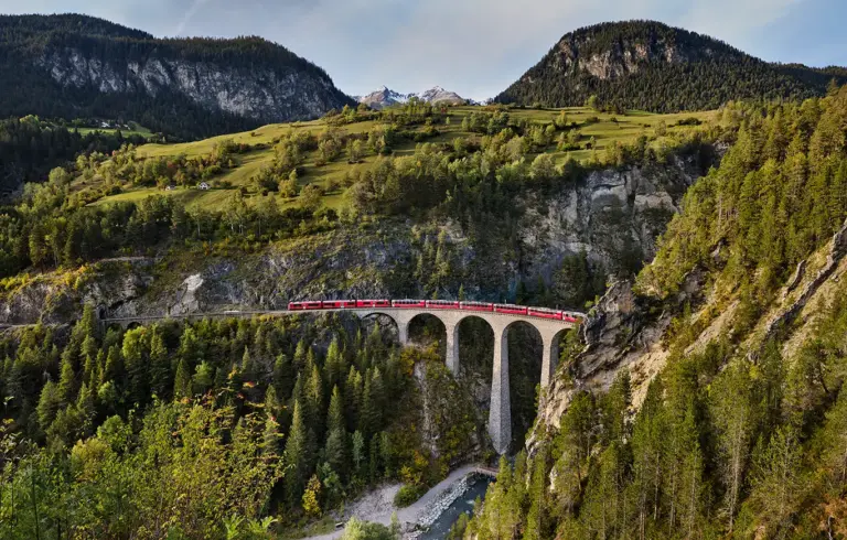 Zug des Bernina Express unterwegs auf dem Landwasserviadukt im Kanton Graubünden in der Schweiz