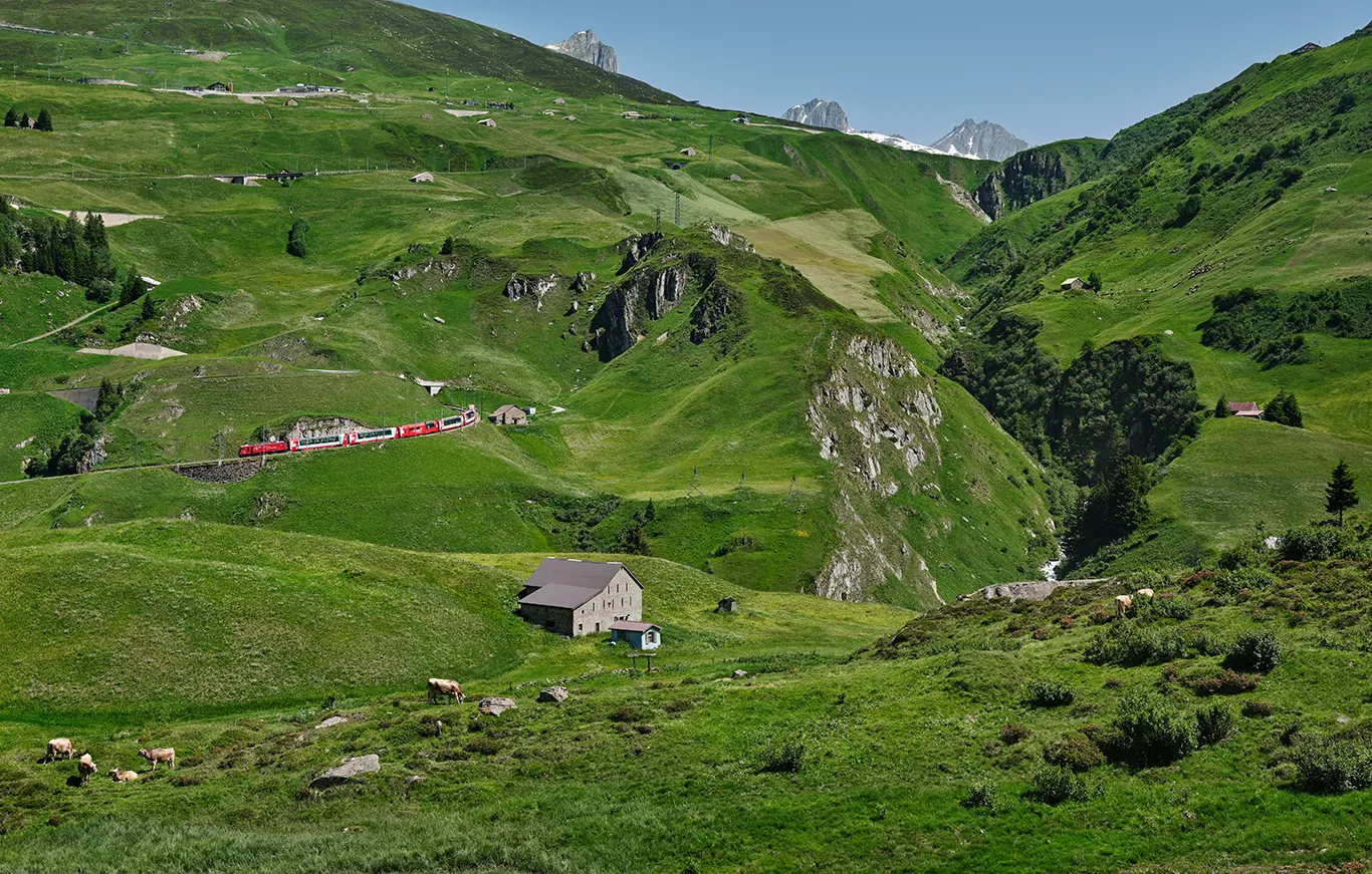 Ein Glacier Express fährt bergab auf der Bahnstrecke an der Westrampe des Oberalppasses bei Andermatt