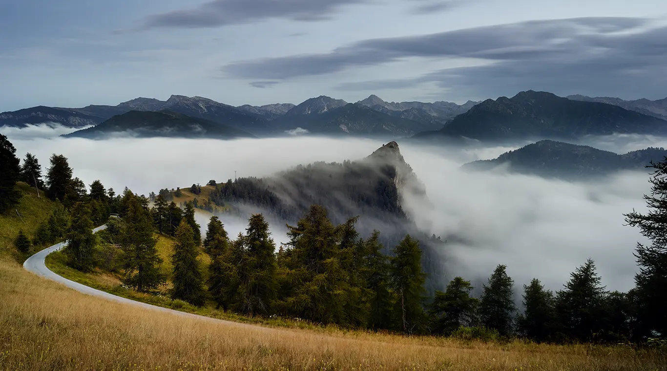Im Vordergrund die enge, teils einspurige Südrampe aus dem Maira-Tal zum Colle di Sampeyre. Dahinter der Monte Bettone wie eine Klippe in einem weichen, weißen Nebelmeer