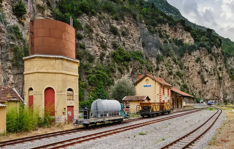 ocker und gelbfarbener Bahnhof von la Tinée mit Wasserturm an der Bahnstrecke des Train des Pignes (Pinienzapfenzug)